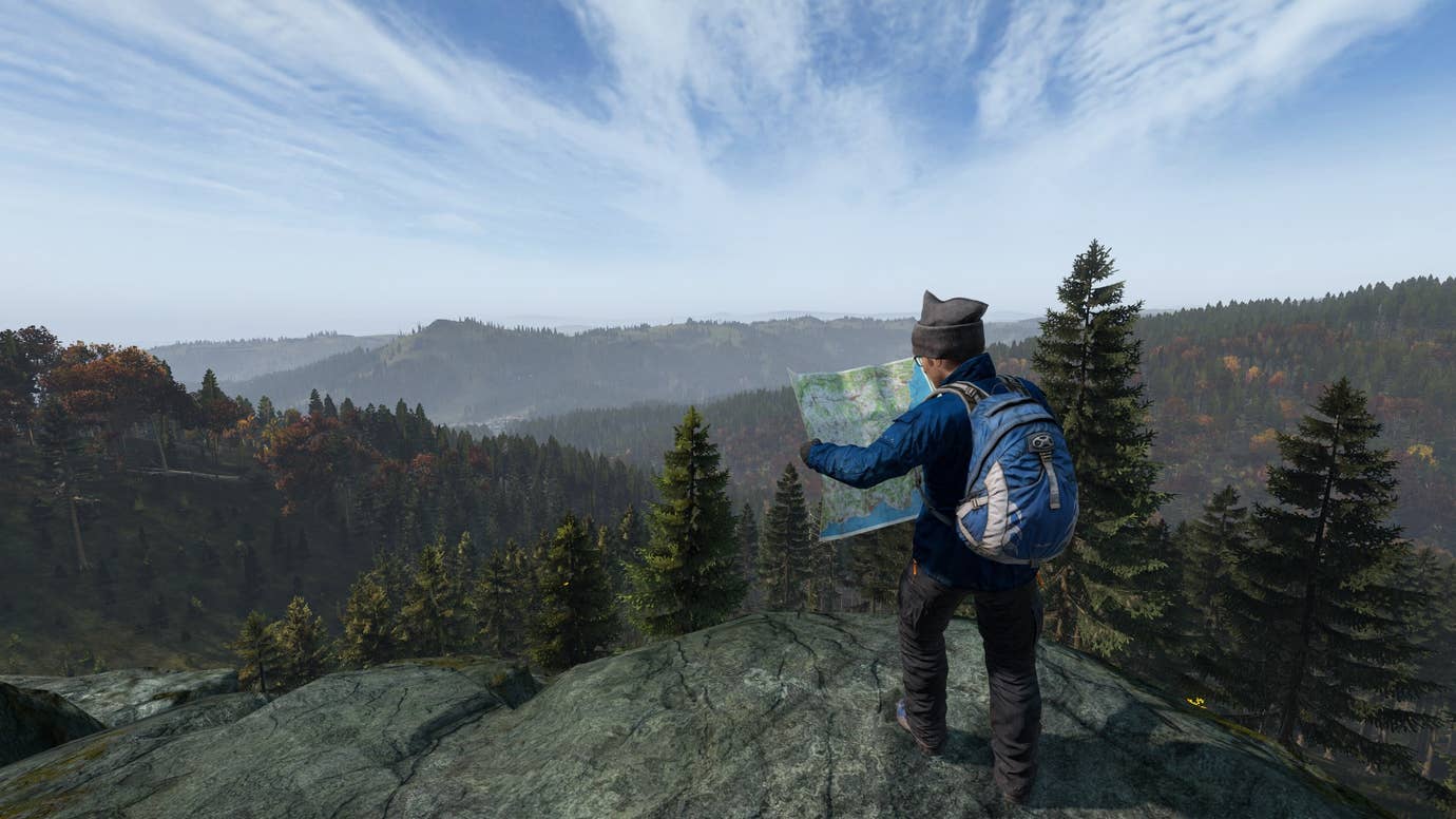 In DayZ, a survivor checks his map while looking out over Chernarus.